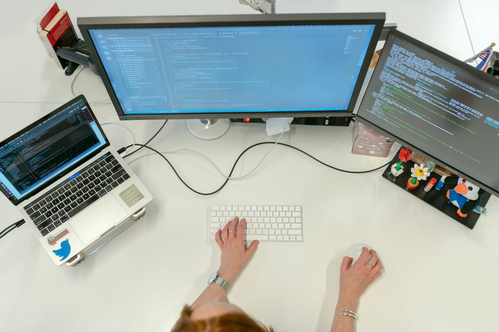 Overhead view of a developer working at a desk with a laptop and two external monitors, the kind of workstation the TeamPCP supply-chain attacks targeted