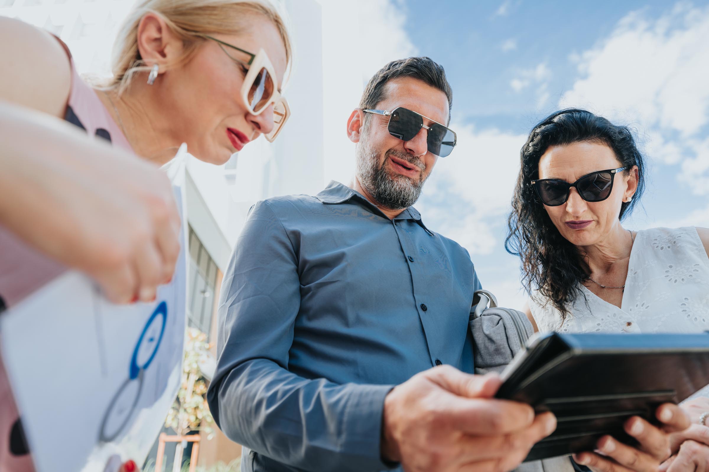 Three adults looking at information together on a tablet outdoors